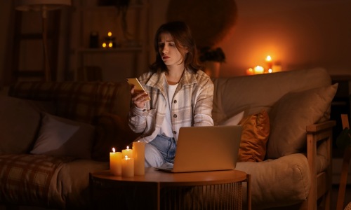 Woman looking at phone by candle light
