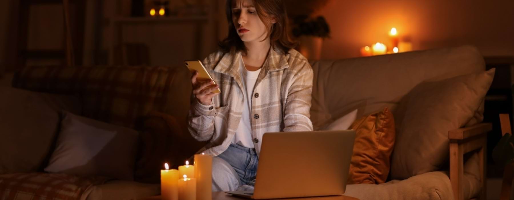 Woman looking at phone by candle light