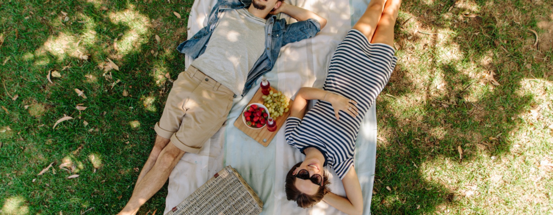 Woman and man laying under a shady tree on a blanket