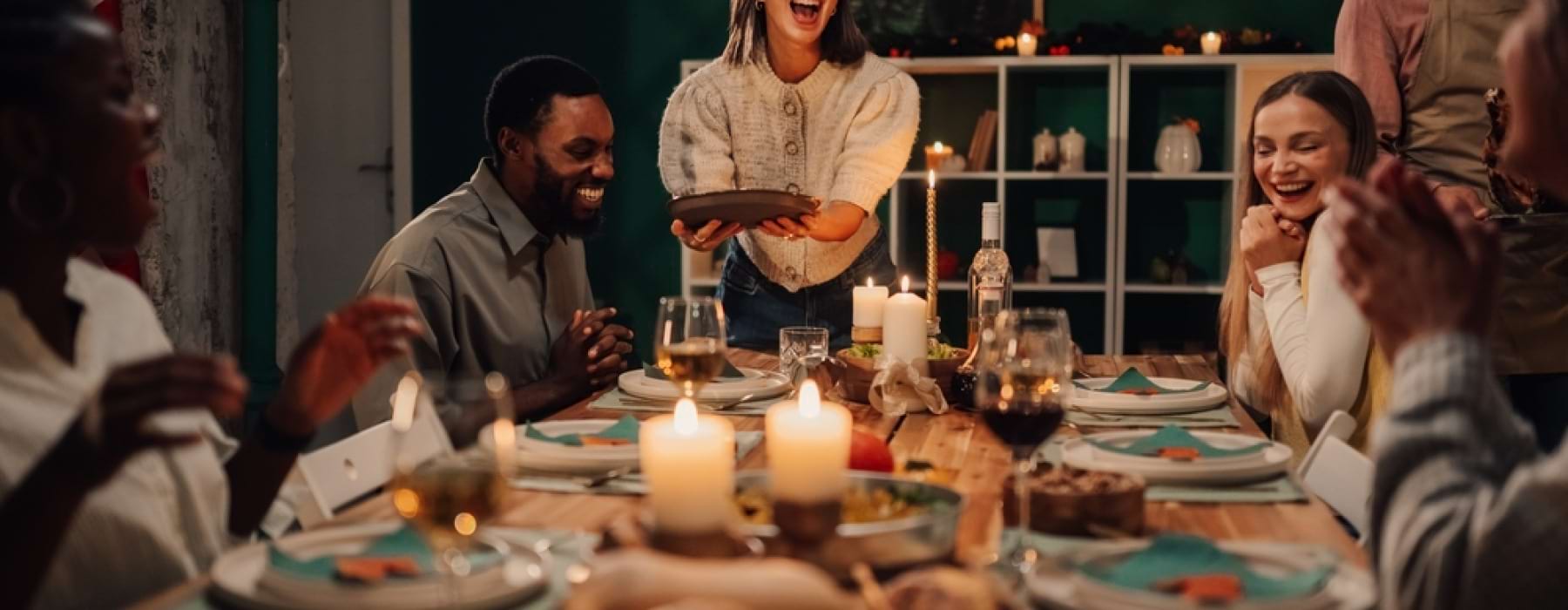 Friends gathering around table, laughing, enjoying a holiday feast