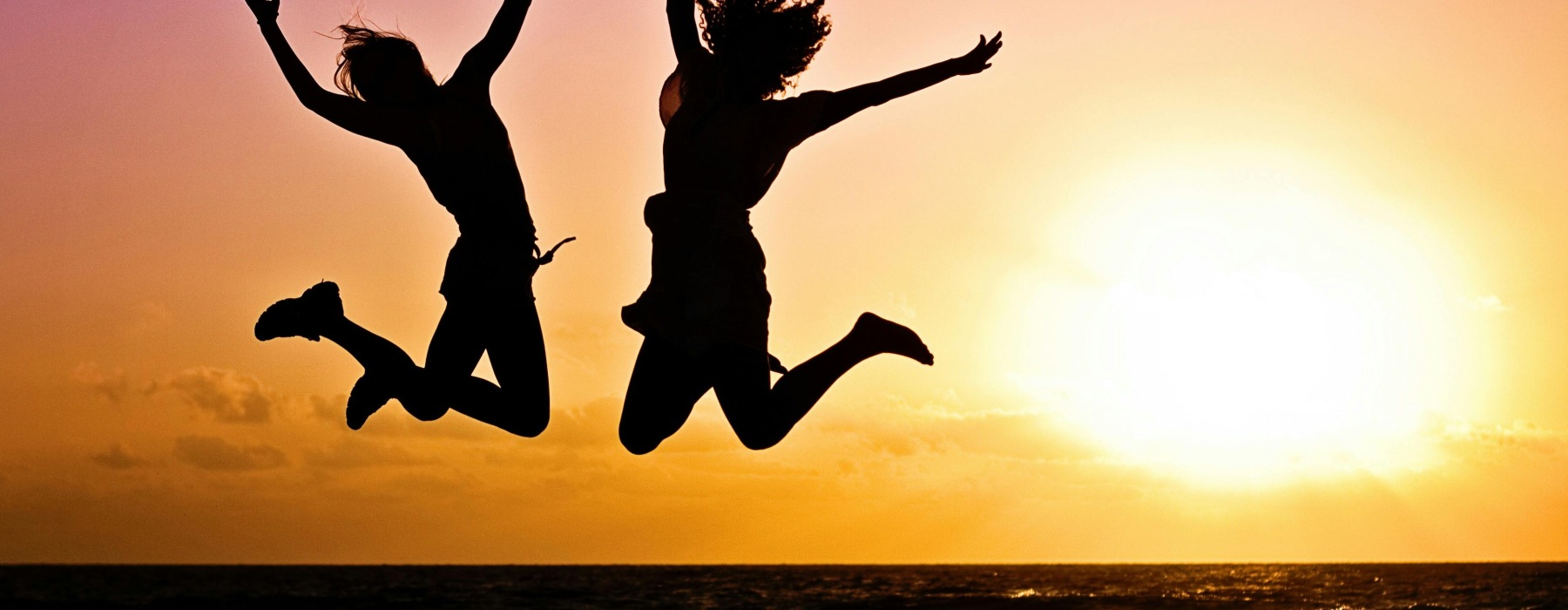 Silhouettes of two people jumping at sunset near Rosharon, Texas, symbolizing fun activities and outdoor adventures