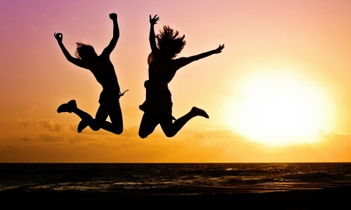 Silhouettes of two people jumping at sunset near Rosharon, Texas, symbolizing fun activities and outdoor adventures