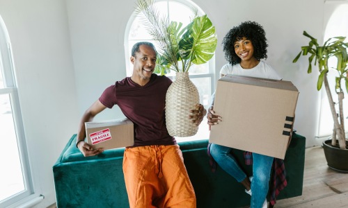 Happy couple moving into a professionally managed rental home in Rosharon, Texas, carrying boxes and decorations.