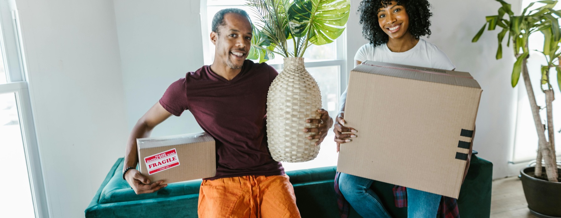 Happy couple moving into a professionally managed rental home in Rosharon, Texas, carrying boxes and decorations.